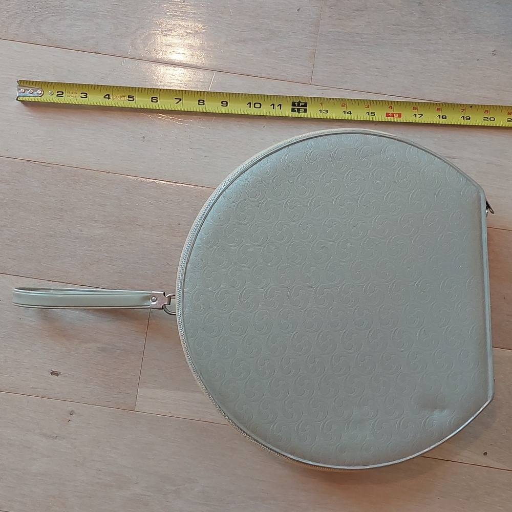 Vintage taupe round case with wrist strap.